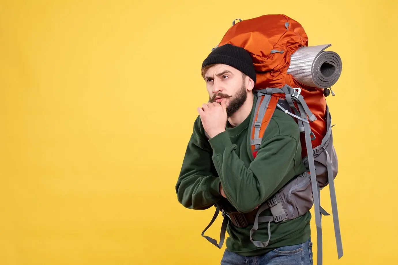 Draufsicht auf ein Reisekonzept mit einem jungen Mann mit Rucksack, der tief in Gedanken ist.